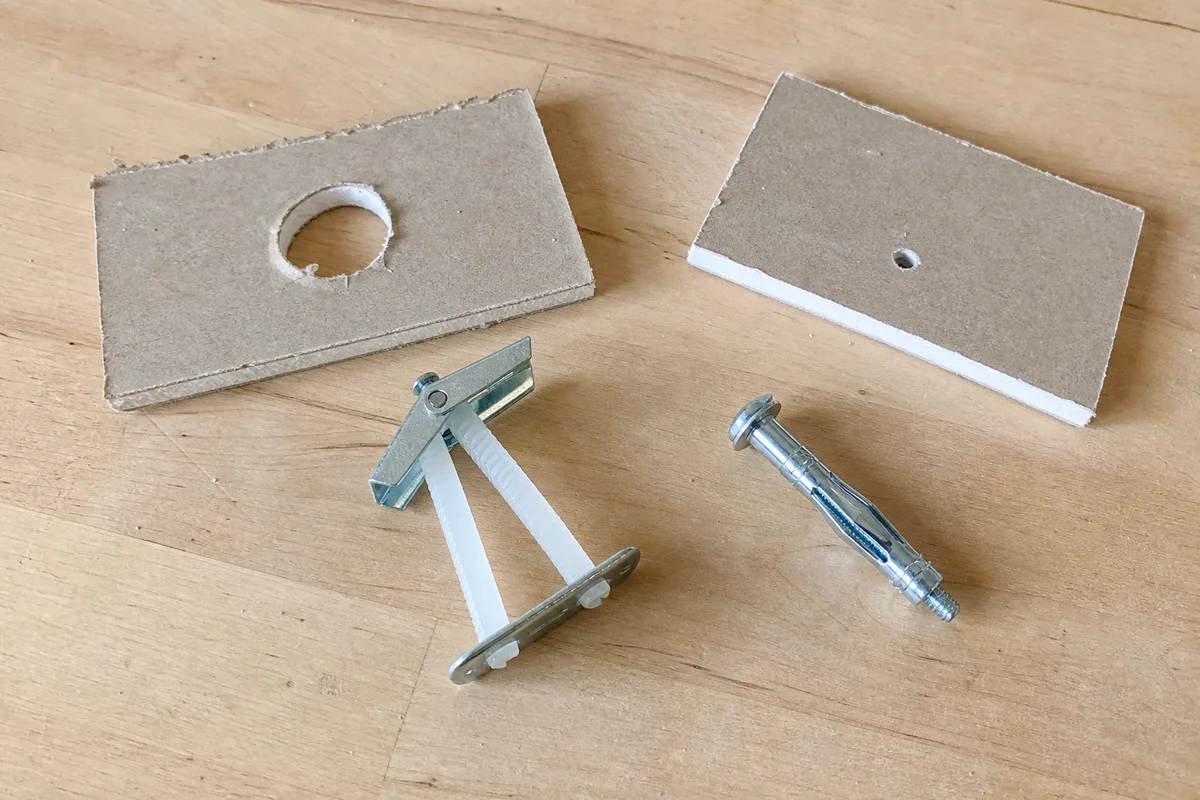 A strap toggle anchor and a molly bolt next to the holes they require