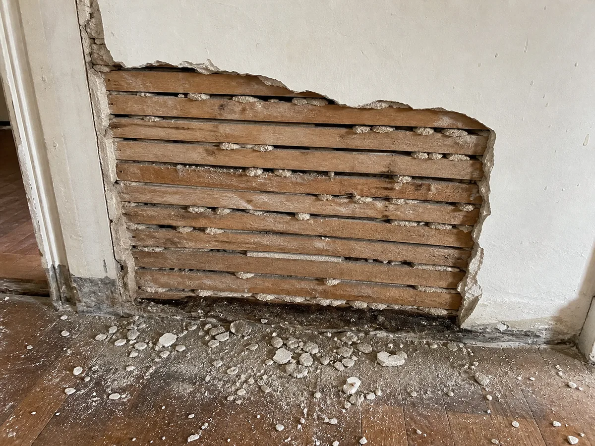 An older wall with plaster over wood lath visible where a section is open