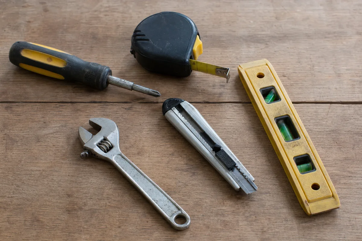 A basic home repair tool kit laid out on a workbench