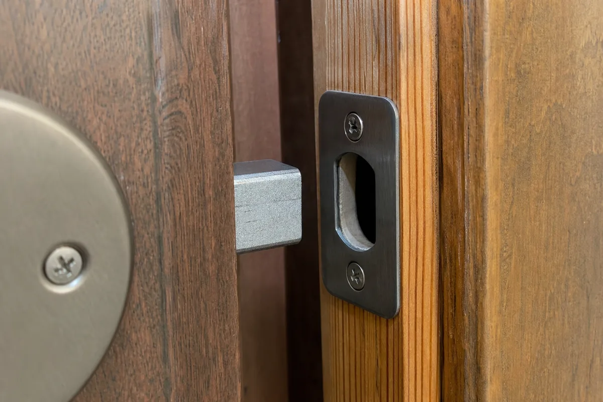 A deadbolt and strike plate on a wooden door frame